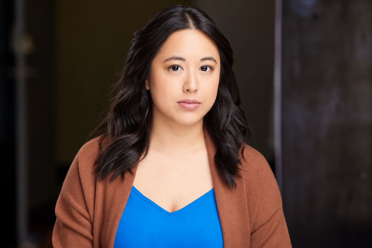 Tiffany Iris — Dramatic headshot in a brown cardigan and blue top