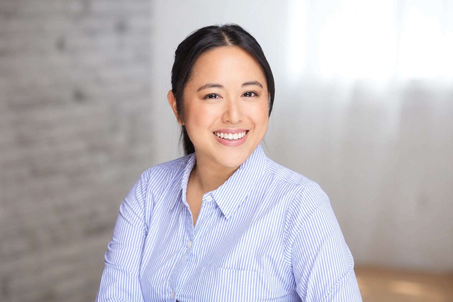 Tiffany Iris — Smiling headshot in a blue and white striped shirt